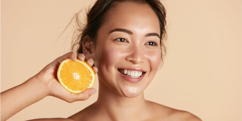 girl holding an orange with glowing skin