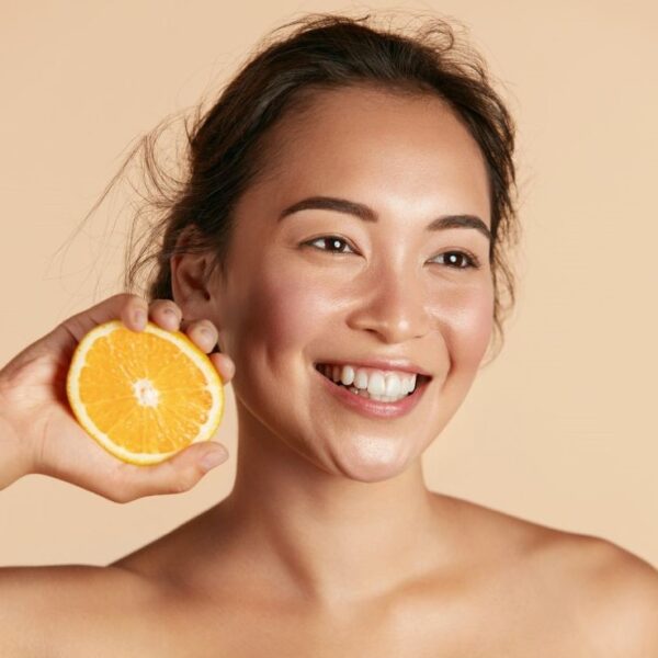 girl holding an orange with glowing skin