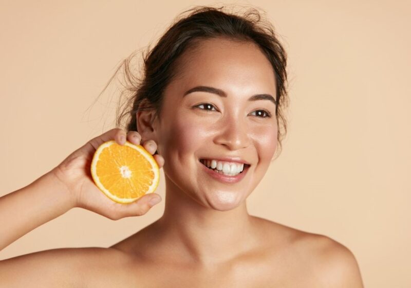 girl holding an orange with glowing skin