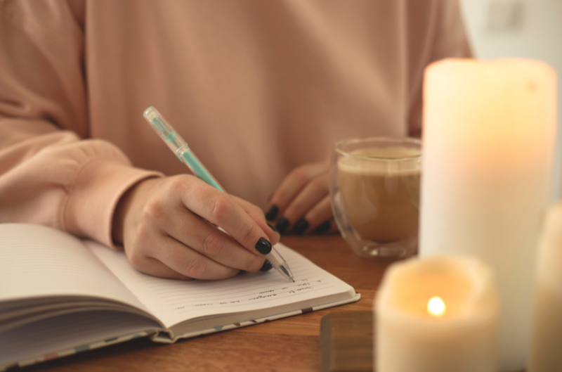 woman journaling with coffee and candles lit